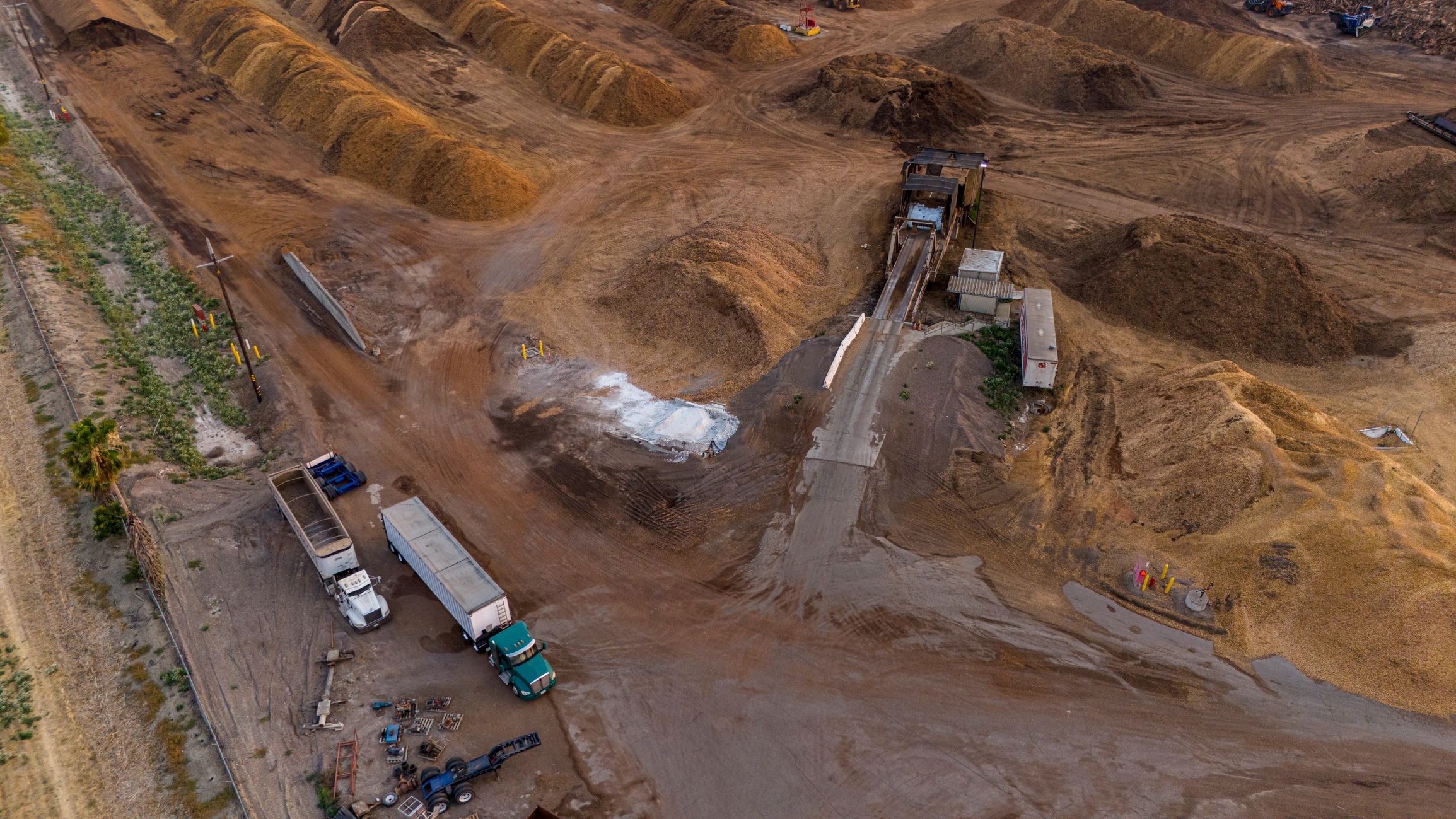 Operação logística com caminhões e materiais em área de apoio